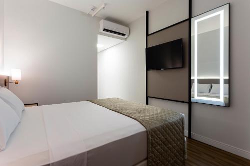 a small bedroom with a bed and a window at Slaviero Rondonópolis Centro in Rondonópolis
