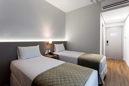a hotel room with two beds and a window at Slaviero Rondonópolis Centro in Rondonópolis
