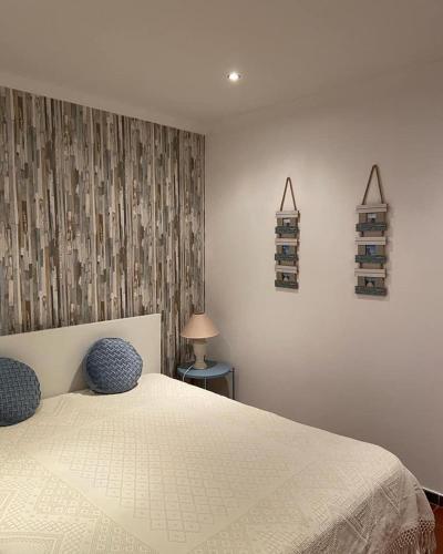 a bedroom with a white bed with two blue pillows at Alojamento JCP in Bombarral