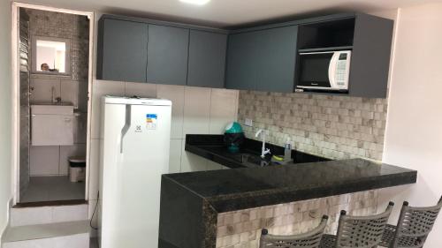 a kitchen with black cabinets and a white refrigerator at Pousada Beach Claudia in Maragogi