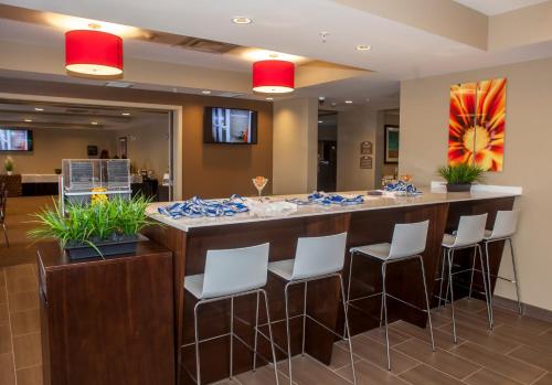 a restaurant with a large bar with white stools at Microtel Inn & Suites by Wyndham Lloydminster in Lloydminster