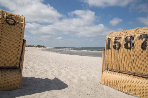 two wicker chairs sitting on a sandy beach at Hotel Strandräuber in Kalifornien