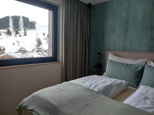 a bedroom with a bed and a large window at Bergleben Maria Alm - Haus Panorama in Maria Alm am Steinernen Meer