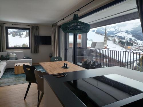 a living room with a table and a large window at Bergleben Maria Alm - Haus Panorama in Maria Alm am Steinernen Meer