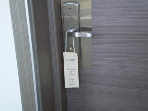 a doorhandle with a sign on a wooden door at Athena Hotel in Milopótamos