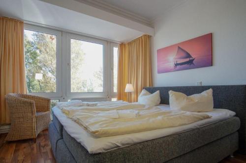 ein großes Bett in einem Zimmer mit einem großen Fenster in der Unterkunft "Strandhotel Heiligenhafen", Wohnung 126 in Heiligenhafen