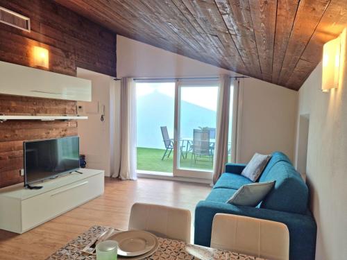 ein Wohnzimmer mit einem blauen Sofa und einem TV in der Unterkunft Profumo di Lago Desenzano-by Goccia di lago in Desenzano del Garda