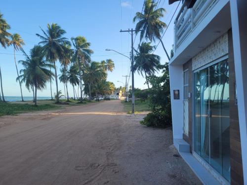 an empty street with palm trees and a building at Pousada Beach Claudia in Maragogi