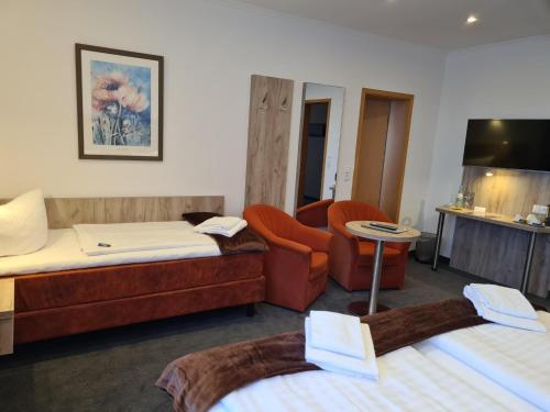 a hotel room with two beds and a chair at WH Hotels Papenburg Zentrum in Papenburg