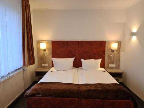 a bedroom with a large bed with two pillows at WH Hotels Papenburg Zentrum in Papenburg