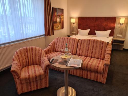 a hotel room with a couch and a bed at WH Hotels Papenburg Zentrum in Papenburg