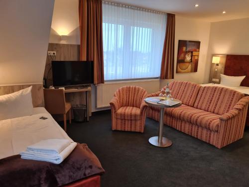 a hotel room with a couch and a tv at WH Hotels Papenburg Zentrum in Papenburg