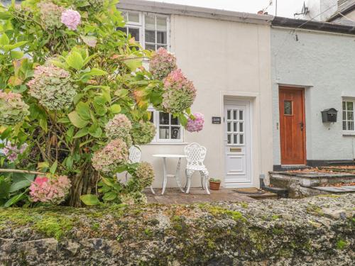a white house with a table and chairs and flowers at Ty Coed in Beaumaris