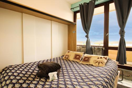 - un chat dormant sur un lit dans une chambre avec fenêtre dans l'établissement HOMEY BELLEVUE - New - Appartement avec une chambre - Parking privé gratuit - Balcon avec belle vue - Netflix et Wifi inclus - A 5 min de la frontière pour rejoindre Genève, à Gaillard
