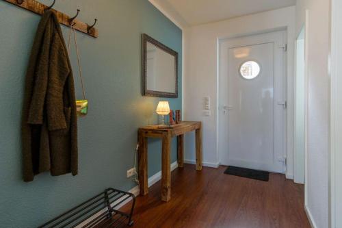 un couloir avec une table, un miroir et une porte dans l'établissement Ferienhaus-Luv, à Heiligenhafen