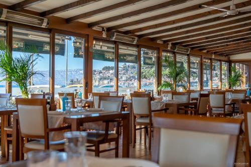 a restaurant with tables and chairs and windows at Tino Hotel & SPA in Ohrid