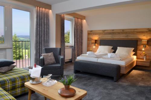 um quarto de hotel com uma cama, um sofá e uma mesa em Hotel Kaiseralm em Bischofsgrün