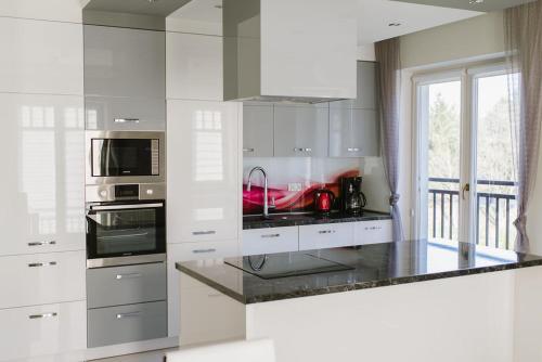 a kitchen with white cabinets and a black counter top at Apartament 15 Delux- Bliżej Zdroju in Polanica-Zdrój