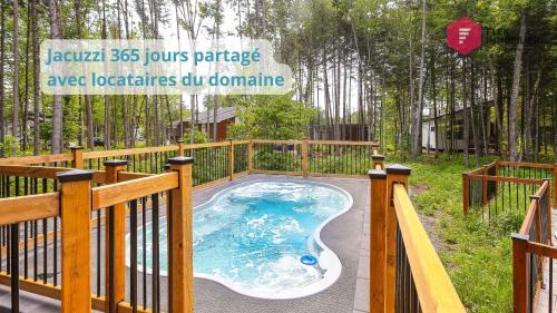 a hot tub on a deck with a fence at La Fleur Urbaine de Portneuf : 2.5 bathrooms, Hot tub, Sauna and Pool in Pont-Rouge