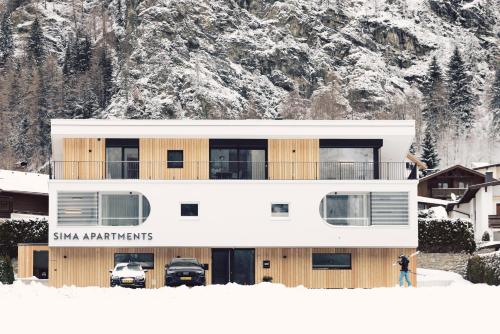 a man standing in the snow in front of a building at Sima-Apartments in Längenfeld