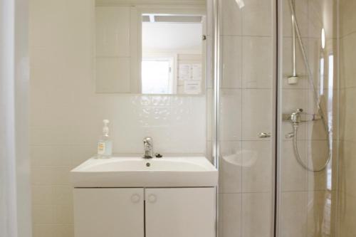 a white bathroom with a sink and a shower at Topcamp Havblikk - Helgeland in Nesna