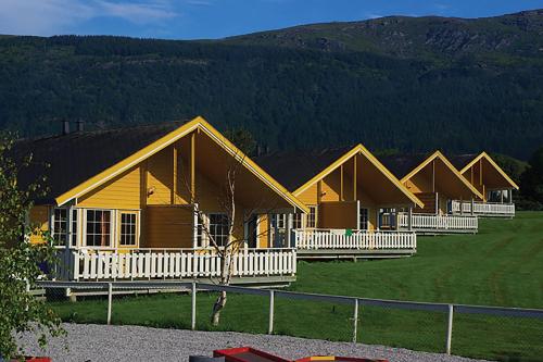 una fila de lodges en un campo junto a una montaña en Topcamp Havblikk - Helgeland, en Nesna