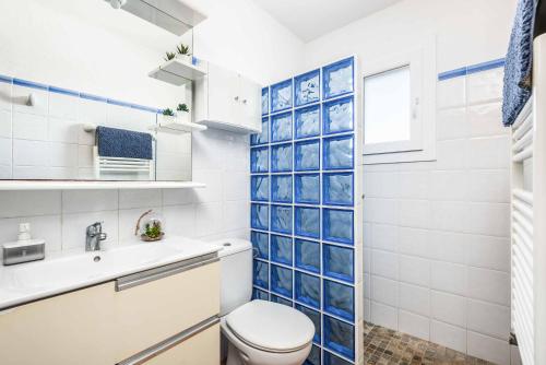 a bathroom with a toilet and a blue tile wall at Villa Mimosa in Binibeca