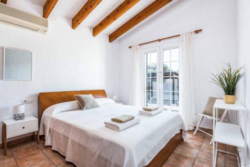 a white bedroom with a large bed and a window at Villa Mimosa in Binibeca