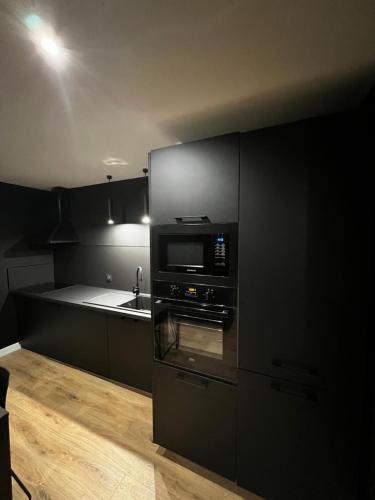 kuchnia z czarnymi szafkami i kuchenką mikrofalową w obiekcie Appartement moderne full black Dunkerque centre w mieście Dunkierka