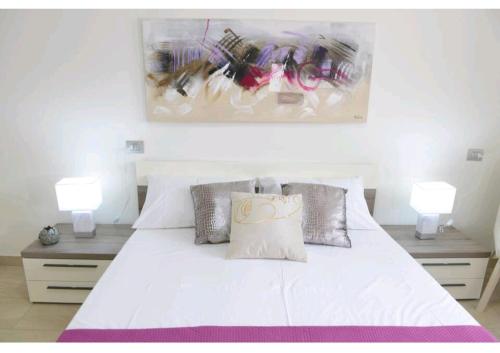 a bedroom with a white bed with two lamps at Benny's House in Alghero