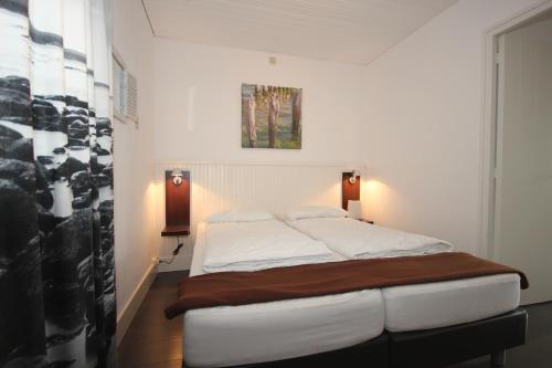 1 dormitorio con 1 cama en una habitación con paredes blancas en Appartement Walvis nr. 14B, en Vrouwenpolder