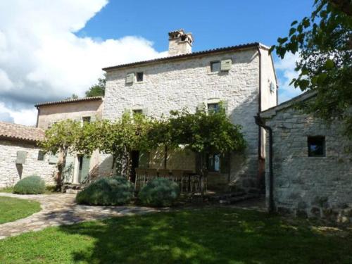 un gran edificio de piedra con un árbol en el patio en At Home In Istria- Villa Stancia Cicada, en Žminj