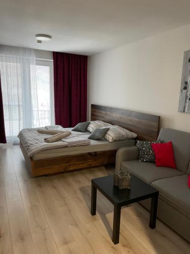 een slaapkamer met een bed, een bank en een tafel bij Apartmán Diamond 2 in Podhájska