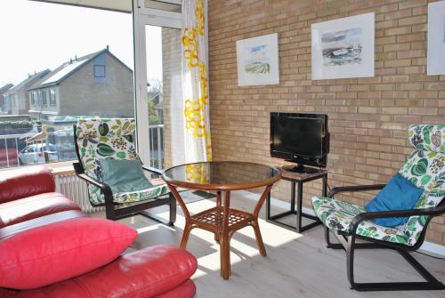 Un balcón con mesa y sillas y un televisor. en Appartement Walvis nr. 16B, en Vrouwenpolder