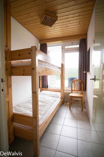 a bedroom with two bunk beds and a chair at Appartement Walvis nr. 20 in Vrouwenpolder