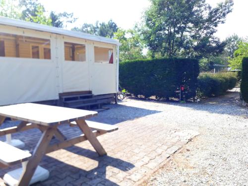 - une table de pique-nique à côté d'une remorque blanche dans l'établissement Bungalow charmant à Saint-Julien-en-Born avec piscine partagée, à Saint-Julien-en-Born