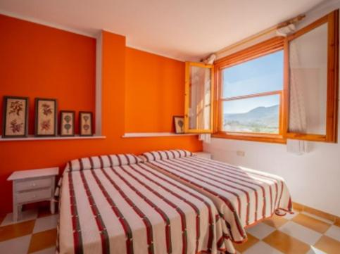 1 dormitorio con paredes de color naranja y 1 cama con ventana en Casa Mistral - Casa Rural Los Cuatro Vientos en Moratalla