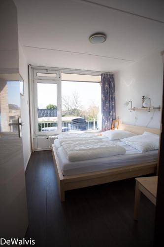 a bedroom with a large bed and a window at Appartement Walvis nr. 26B in Vrouwenpolder