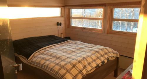 un letto in una stanza con due finestre di Venehovda - cabin at 1000 masl ad Ål