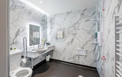 a bathroom with marble walls and a toilet and a sink at High Range Holiday Apartments in Aviemore
