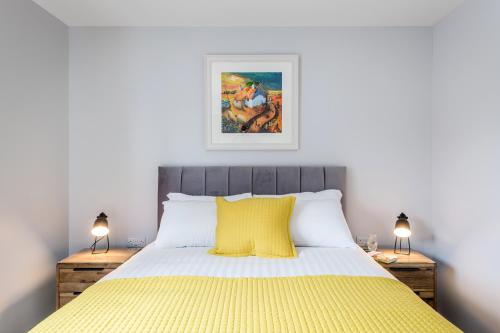 a bedroom with a yellow bed with two lamps at High Range Holiday Apartments in Aviemore
