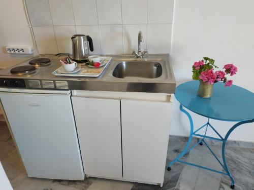 a kitchen with a sink and a table with flowers at Παραθαλασσιο στουντιο Μιχαλιας Sea view studio Michalias Νουμερο 8 in Agia Marina Aegina