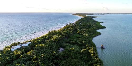 an island in the ocean with a boat in the water at Villa Destiny Tulum beach front luxury villa in Tulum