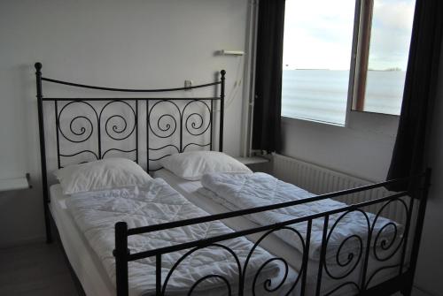 een bed met witte lakens en kussens naast een raam bij Appartement Walvis nr. 9H in Vrouwenpolder