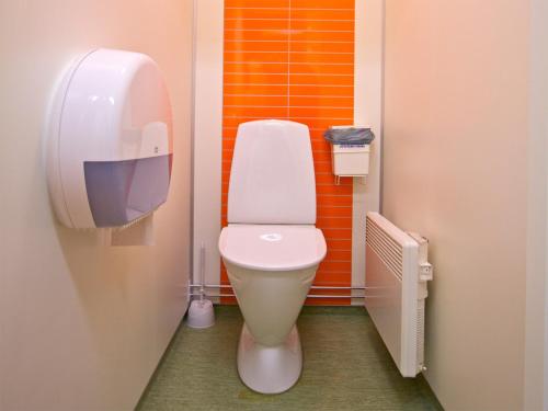La salle de bains est pourvue de toilettes blanches et d'un mur orange. dans l'établissement Gaffelbyn - Sundsvalls Vandrarhem, à Sundsvall