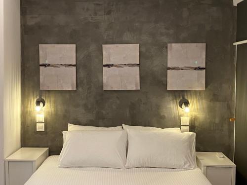 um quarto com uma cama com três pinturas na parede em George House em Atenas