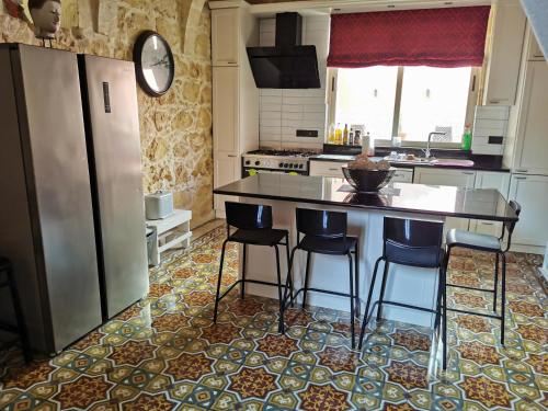 a kitchen with a refrigerator and a counter with stools at 2 Large ensuite Bedrooms in Boutique Style Farmhouse B&B with Pool in Xagħra