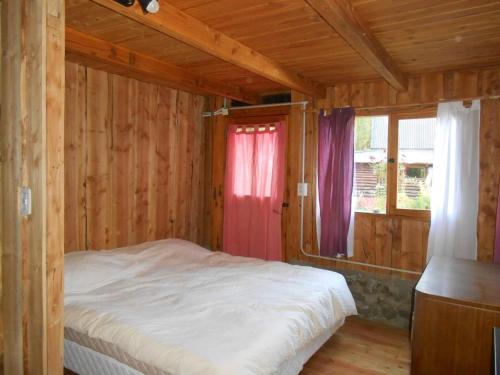 a bedroom with a bed in a wooden cabin at Cabaña La Confluencia, a metros del Río Quemquemtreu y del Río Azul in Lago Puelo