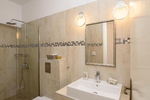 a bathroom with a sink and a shower and a mirror at Galaxy in Aegiali