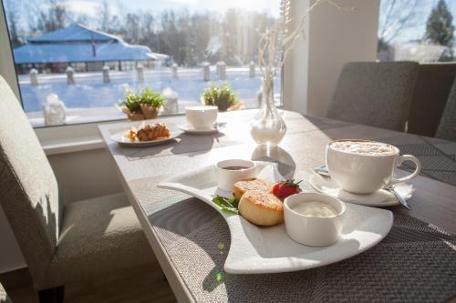 a table with cups of coffee and a plate of food at Парк-отель Медвежьи Озера in Medvezh'i Ozera